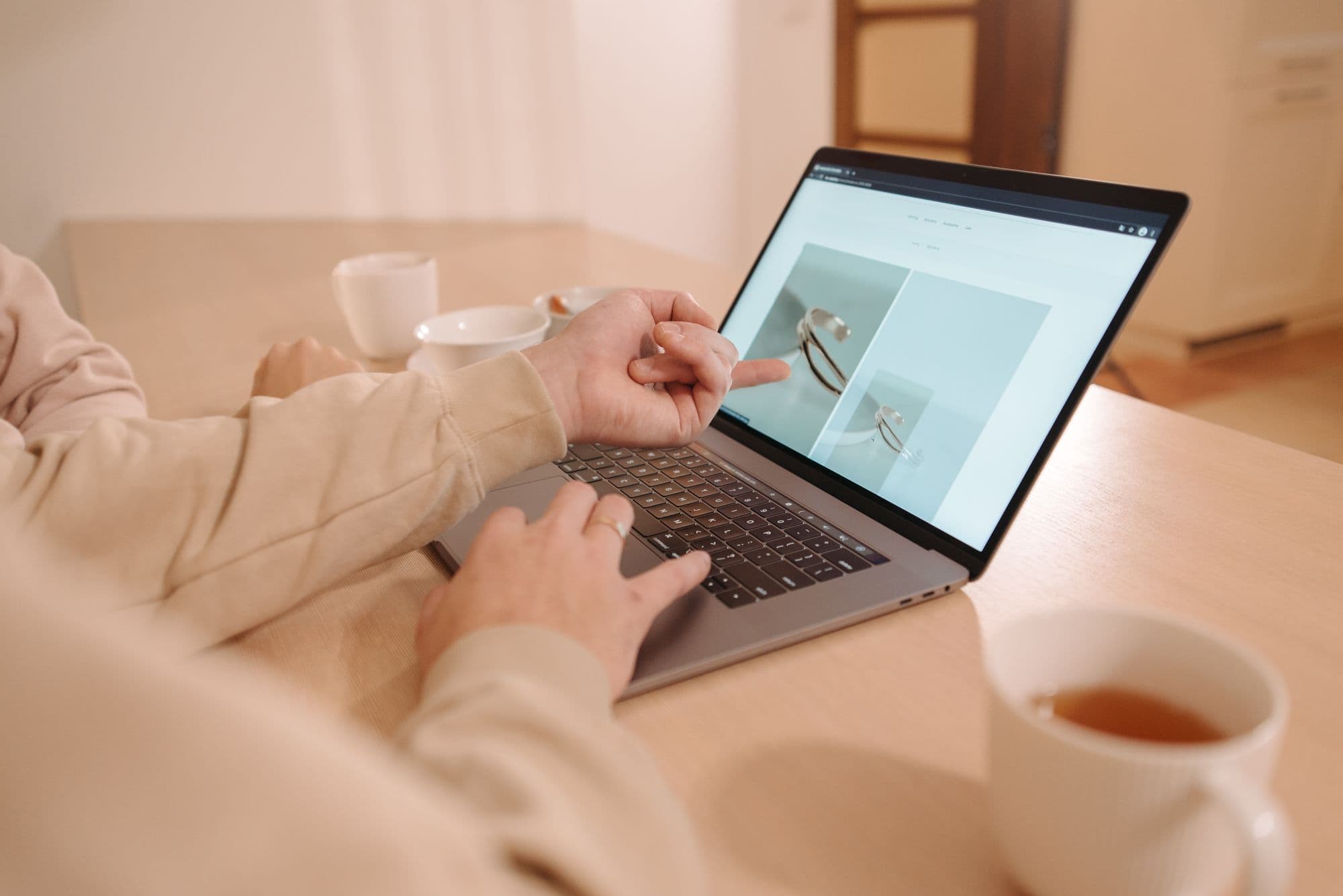 Two people review a web page together on a laptop, one pointing at the screen.