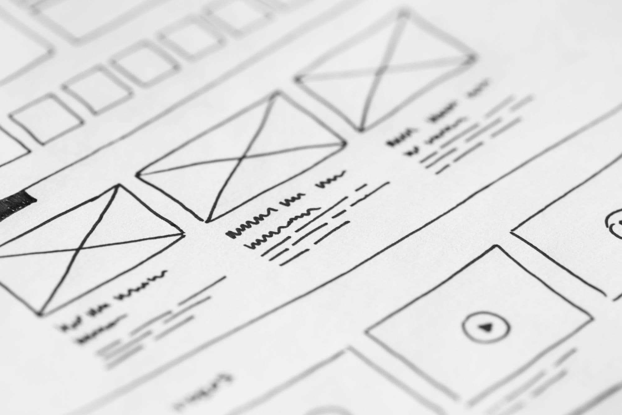 Hand-drawn website wireframes on paper, showing page layouts with image and text blocks.